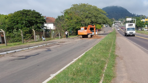 Uma foto ampla da rodovia RSC-287 em que uma escavadeira realiza o trabalho iniciando a construção da travessia urbana de Montenegro