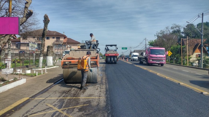 Duas máquinas trabalham simultaneamente sobre a pista, no trecho urbano de Nova Petrópolis. Isso fez com que uma parte da rodovia fique trancada. Do lado direito, um caminhão conduz o fluxo de veículos.