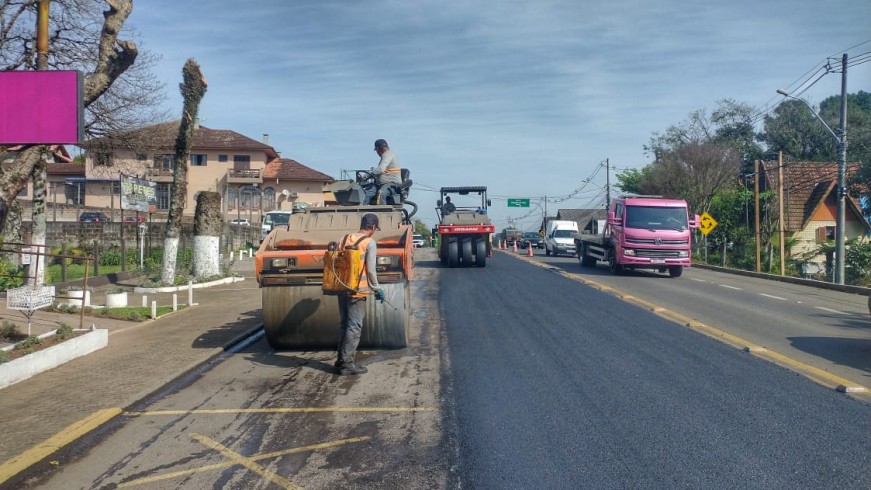 Duas máquinas trabalham simultaneamente sobre a pista, no trecho urbano de Nova Petrópolis. Isso fez com que uma parte da rodovia fique trancada. Do lado direito, um caminhão conduz o fluxo de veículos. 